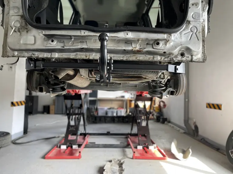 Autoturism ridicat pe elevator în atelierul ProElectric, cu cârlig de remorcare montat
